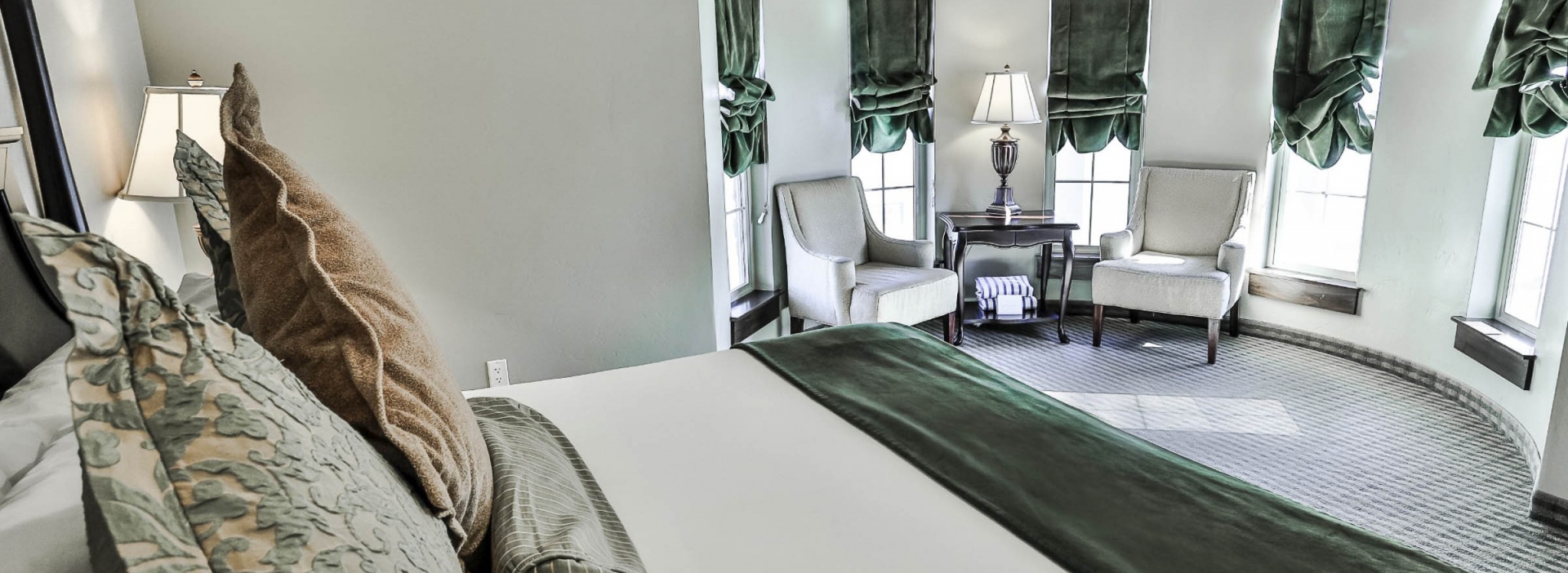 Spacious bed overlooking the curved wall full of large windows in the Mother Spring Suite