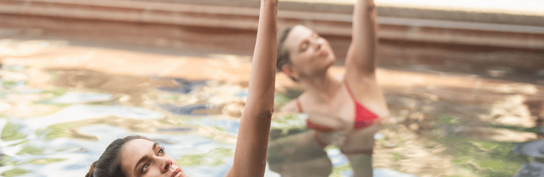 Women practicing aqua yoga in natural hot springs pool at The Springs Resort.