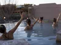 A group of women raising their arms in the water of the hot spring pool