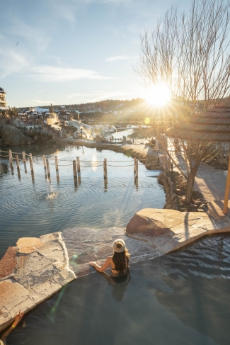 A rearview of a woman watching the view while soaking in the hot spring pool