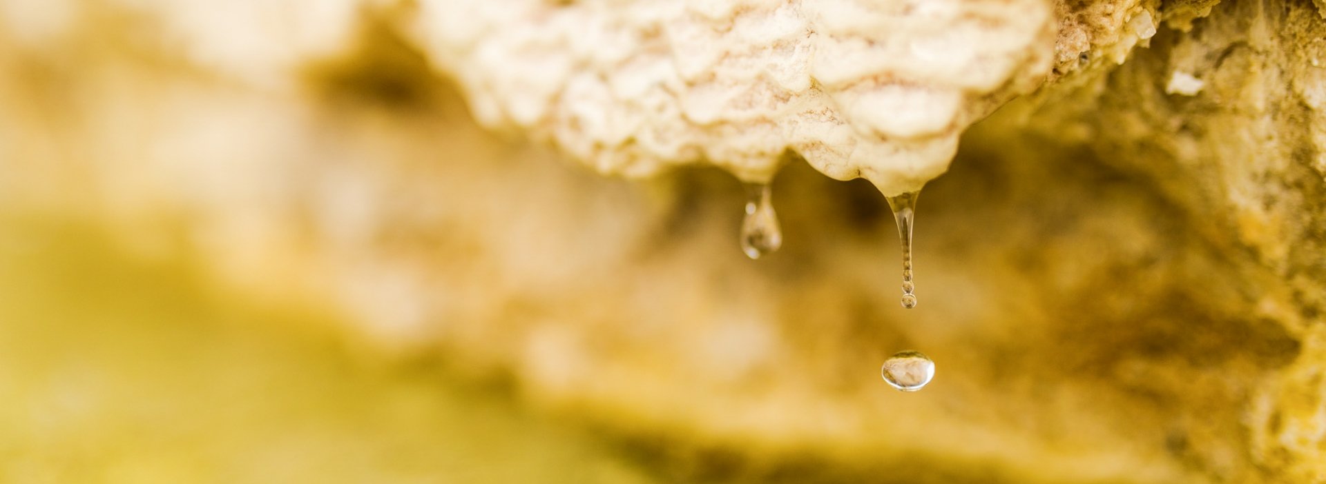 A wide shot of water drops falling from a rock