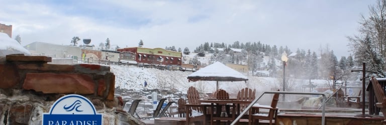 An outdoor hot spring pool steams, its nearby sign reads: 