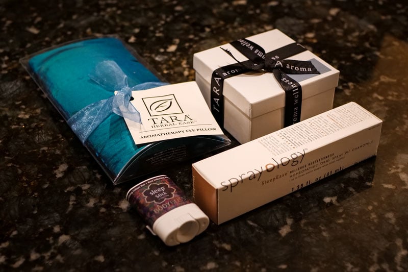 Various wellness items: TARA HERBAL EASE™ AROMATHERAPY EYE PILLOW, a white gift box with 