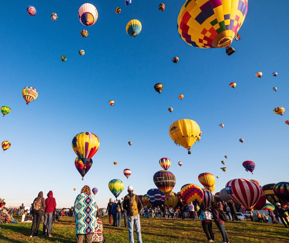 Numerous colorful hot air balloons, including one displaying 