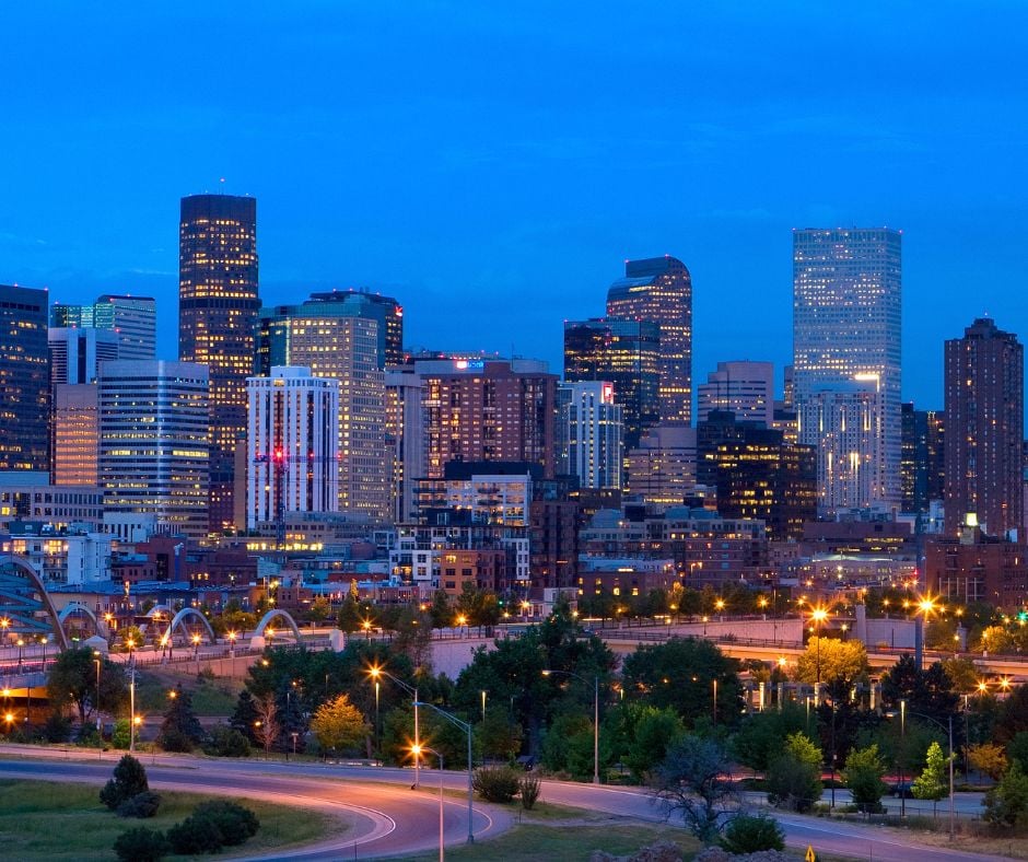 Downtown city skyline glows with countless illuminated windows under a deep blue twilight sky, above winding roads and streetlights. Text: U.S. Bank