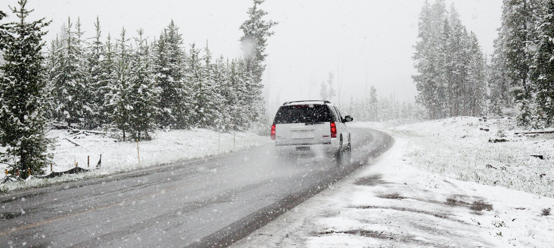 A wide shot of snowy winding roads surrounded by trees and a view of the Colorado mountains