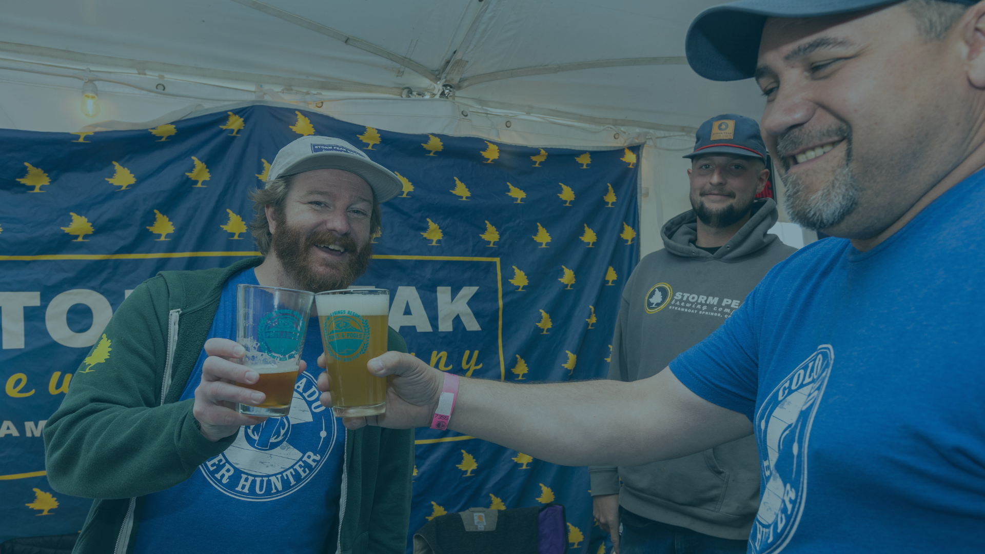 Three smiling men, two toasting with beer glasses under a white tent, in front of a blue banner with yellow tree logos.
Text: TO OAK ny, STORM PEAK Brewing, COLORADO BEER HUNTER, SPRINGS RESORT & POOLS, STORM PEAK Brewing.com STEAMBOAT SPRINGS, CO, COLO BEER, 7355.