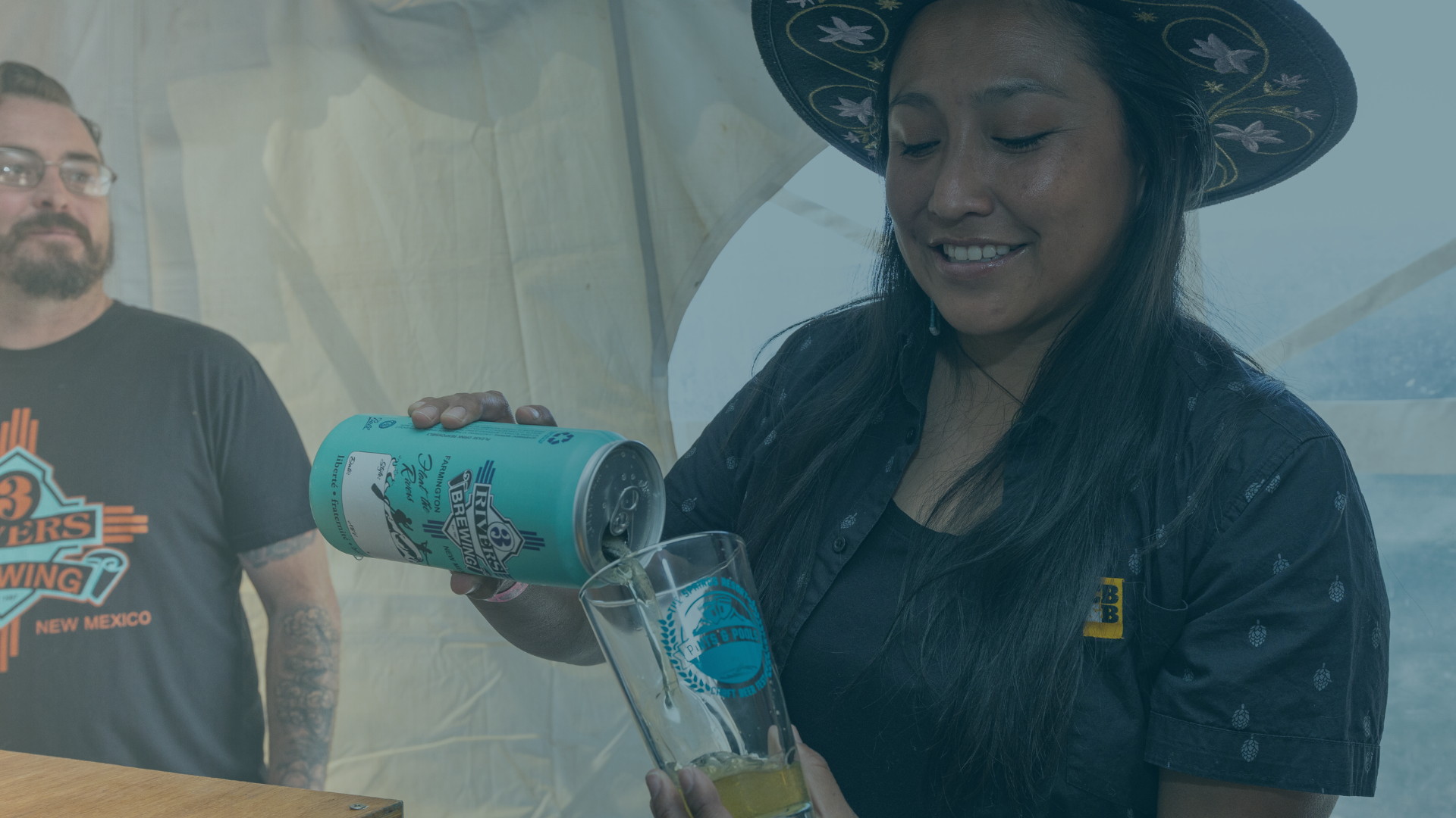 A smiling woman in an embroidered hat pours 