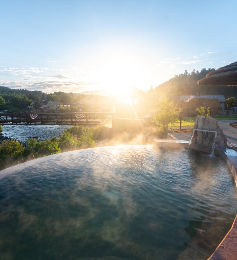 Relaxing hot spring pool at The Springs Resort during sunset.