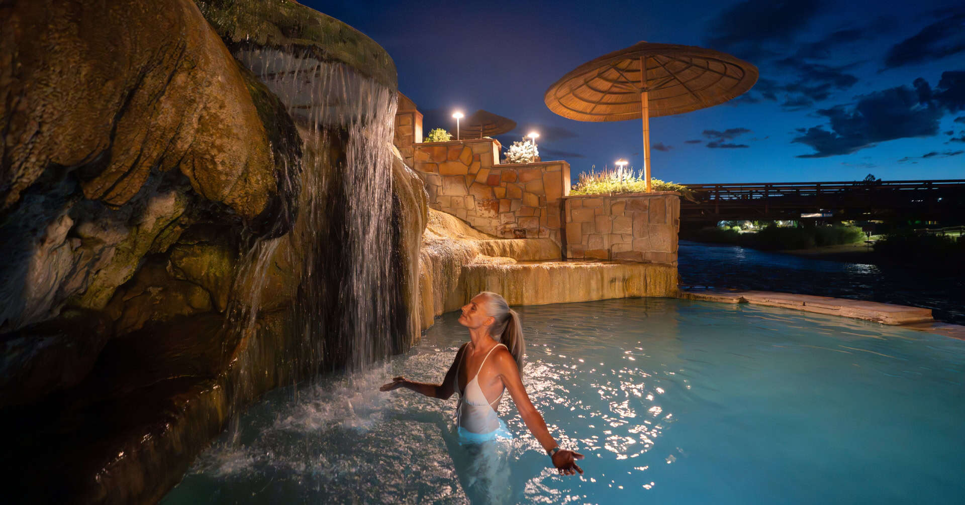 Woman enjoying the hot springs pool at The Springs Resort in Pagosa Springs, Colorado during evening.