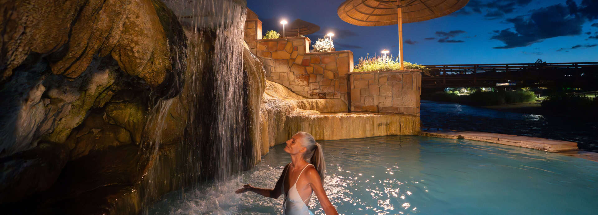 Woman enjoying the hot springs pool at The Springs Resort in Pagosa Springs, Colorado during evening.