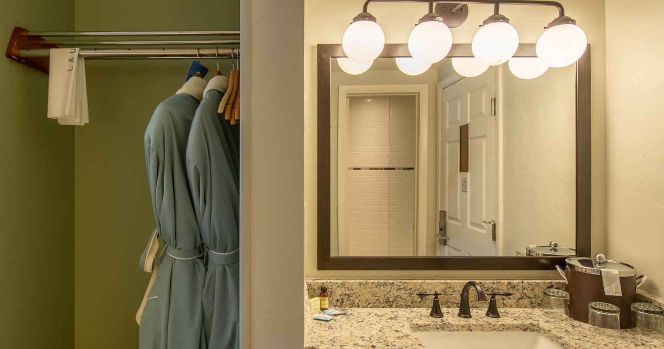 Two blue bathrobes hang next to folded white towels labeled 
