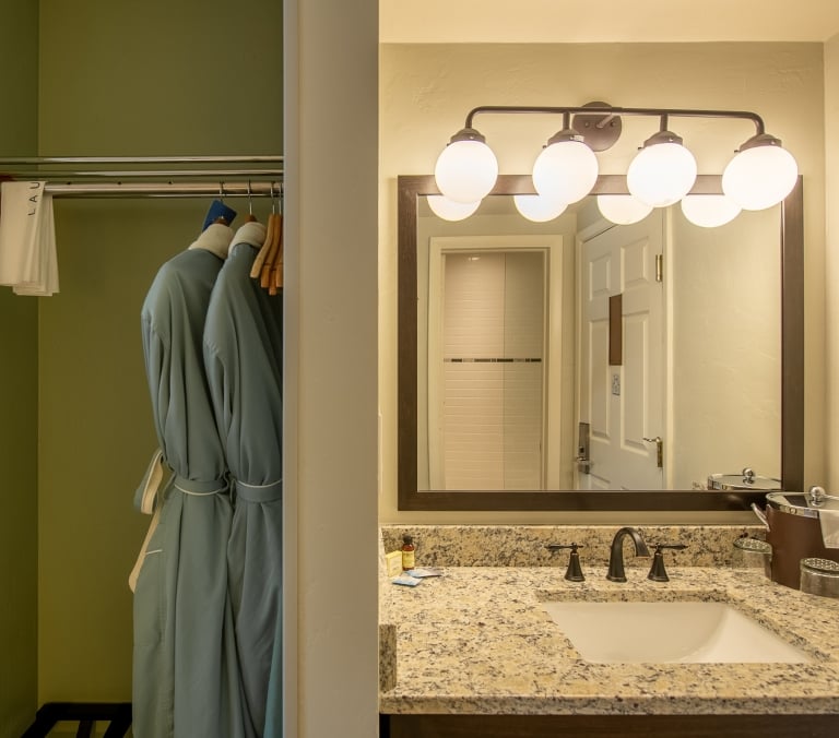 Two blue bathrobes hang next to folded white towels labeled 
