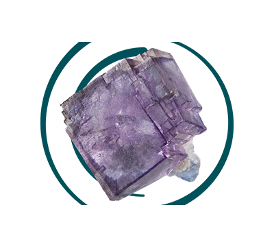 A large, rough-hewn purple crystalline mineral with visible facets is positioned diagonally, partially enclosed by a dark teal double ring on a white background.