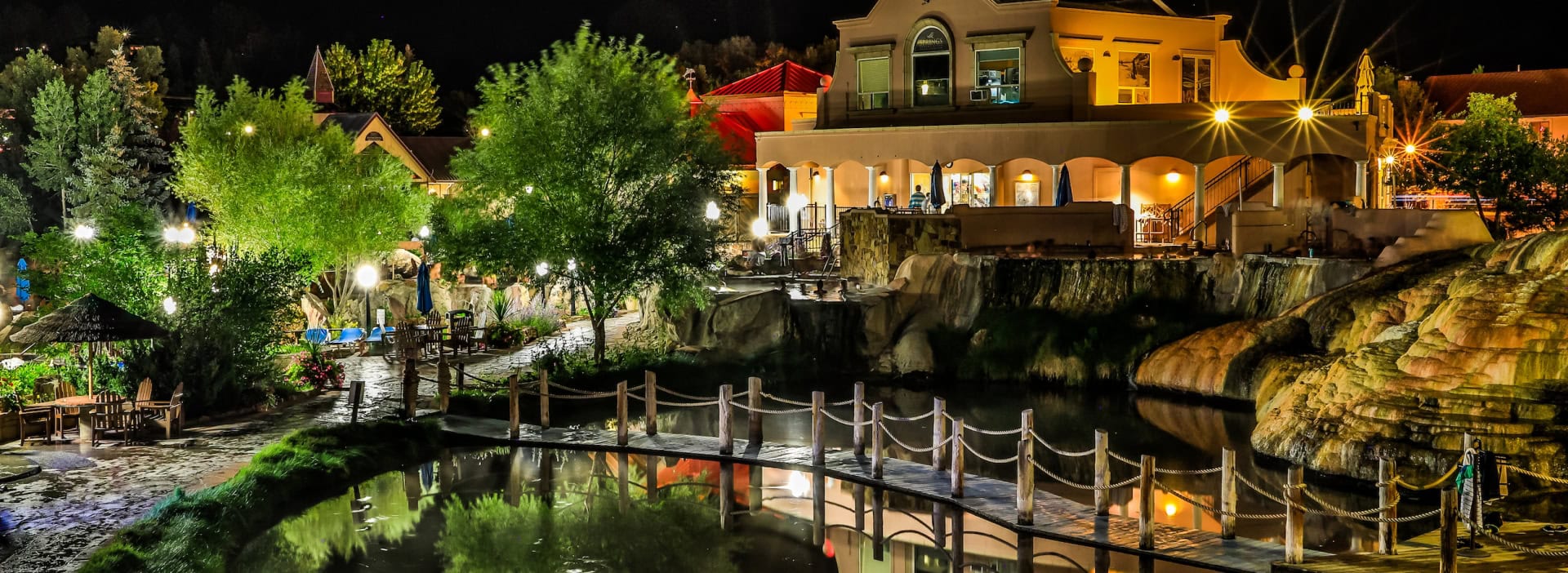 Night view of The Springs Resort with illuminated buildings and reflection on the water.