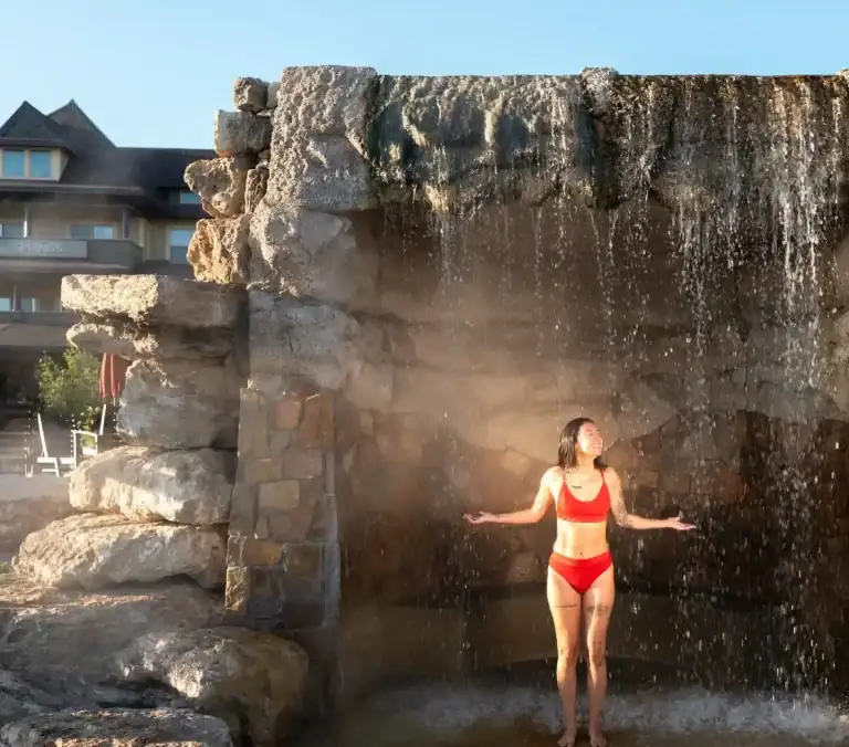 Woman enjoying outdoor waterfall at The Springs Resort in Hot Springs, Arkansas.