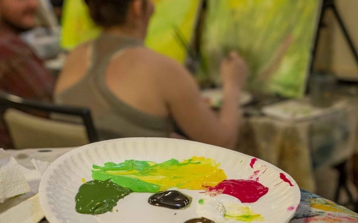 Artist painting a colorful landscape at The Springs Resort during onsite art session.