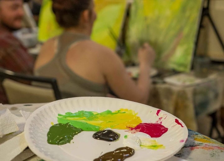 Artist painting a colorful landscape at The Springs Resort during onsite art session.
