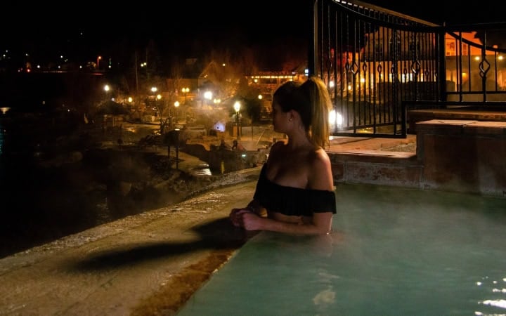 Woman relaxing in hot spring pool at The Springs Resort during nighttime.