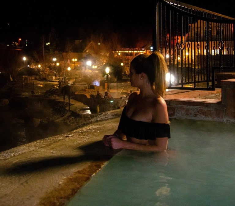 Woman relaxing in hot spring pool at The Springs Resort during nighttime.