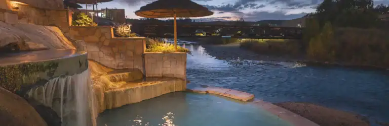 Outdoor hot spring pool with waterfalls and sunset view at The Springs Resort.