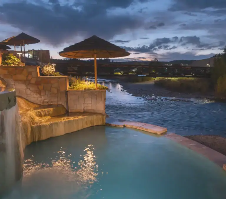 Outdoor hot spring pool with waterfalls and sunset view at The Springs Resort.