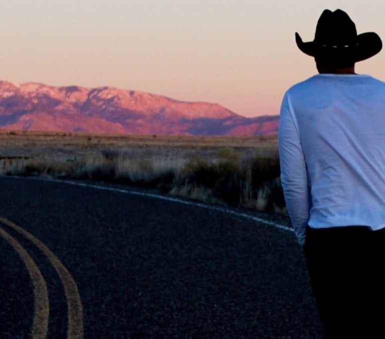 Person walking on road with mountains at sunset near The Springs Resort.
